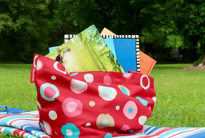 Picknickdecke mit Büchertasche auf Wiese
