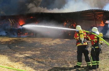 Foto von zwei Feuerwehrleuten, die gerade einen größeren Brand löschen