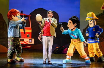 Foto einer Szene aus dem Theaterstück: die Hauptdarsteller und ein Feuerwehrauto