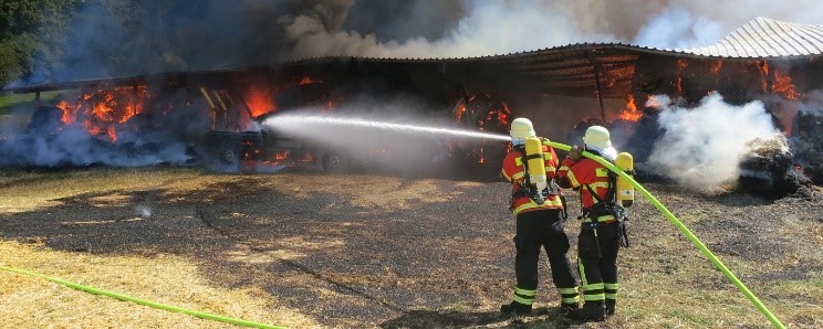 Foto von zwei Feuerwehrleuten, die gerade einen größeren Brand löschen