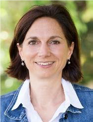 Foto der Autorin: Lächelnde Frau mit halblangen braunen Haaren, weißer Bluse und Jeansjacke